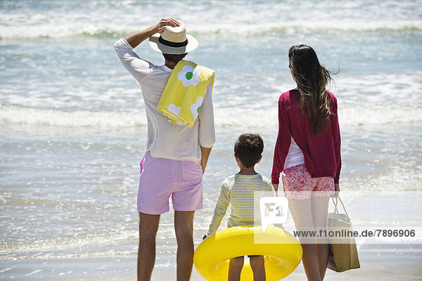 Junge mit seinen Eltern auf das Meer am Strand blickend