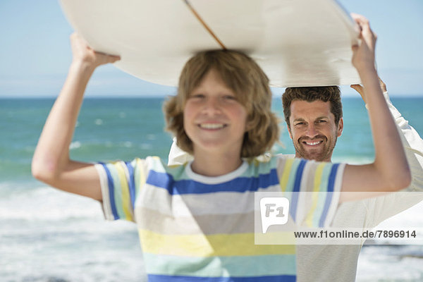 Mann und Sohn mit Surfbrett am Strand