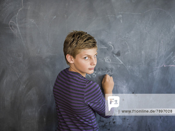 Boy writing on a blackboard in a classroom