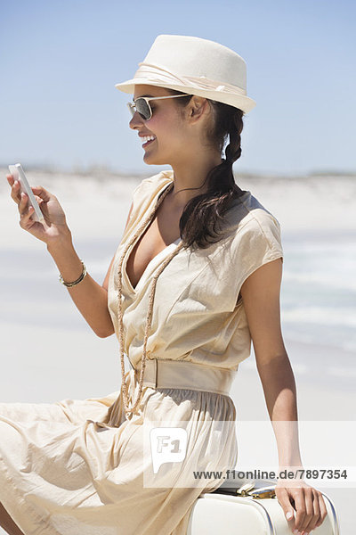 Schöne Frau SMS auf einem Handy am Strand