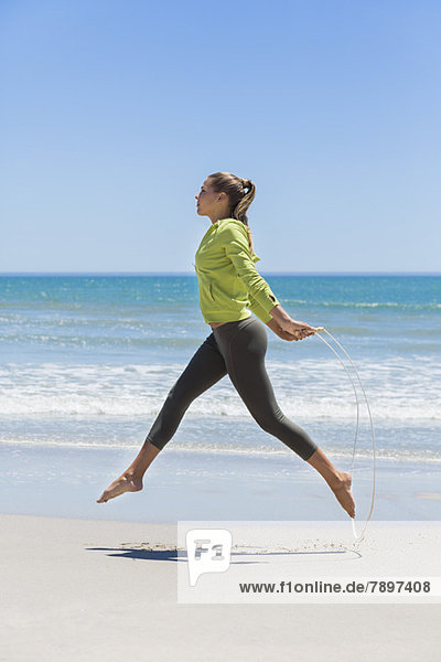 Woman jumping rope on the beach