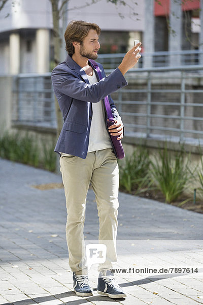 Mann beim Fotografieren mit dem Handy auf der Straße