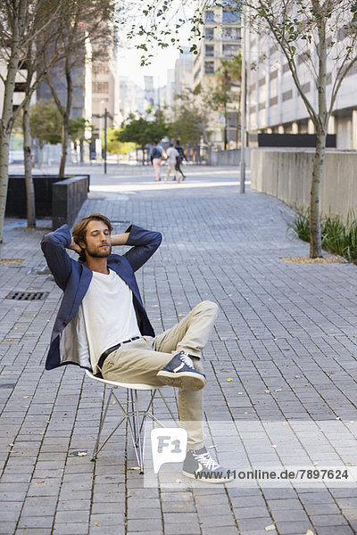 Mann entspannt sich auf einem Stuhl auf der Straße