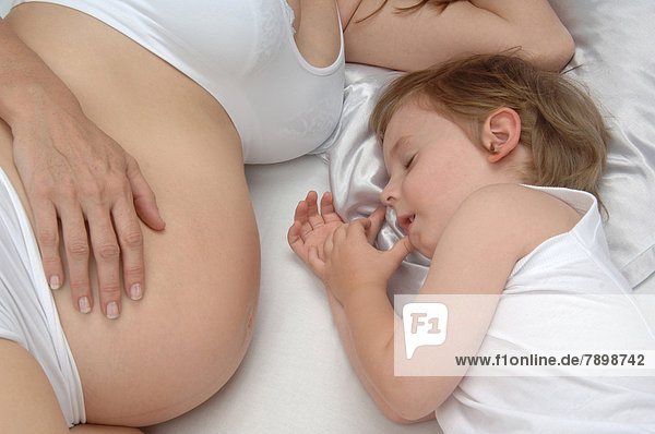 Junge liegt an Bauch von schwangerer Mutter