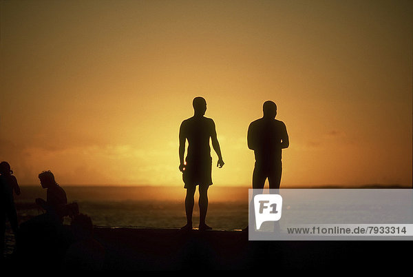 Silhouettes of people on the beach at sunset