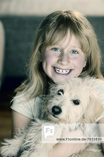 Mädchen  neun Jahre  schmust mit einem jungen Mischlingshund