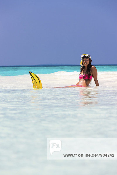 Young woman  about 20  sitting on a sandbank with snorkeling gear