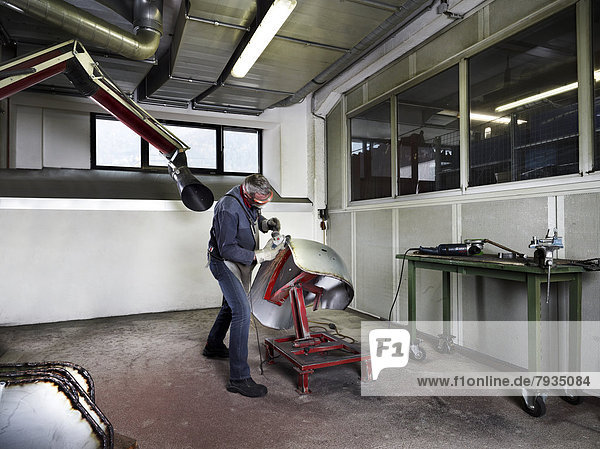 Worker grinding a fender in a workshop