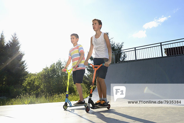 Two boys with scooters on a sports place