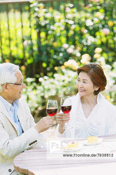 Senior couple cheering with red wine