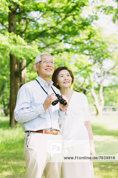 Senior couple with binoculars looking away
