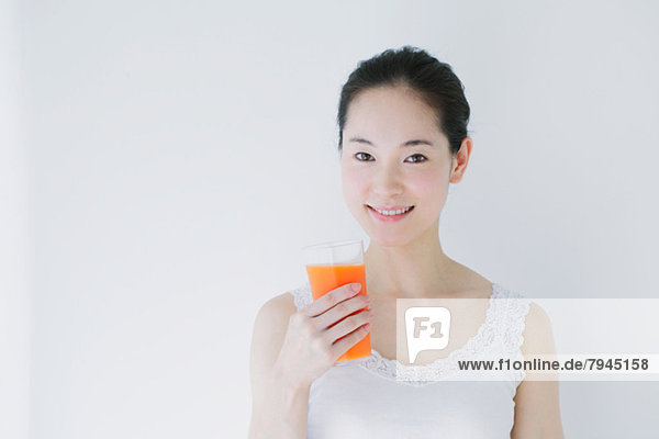 Young woman with vegetable juice smiling at camera