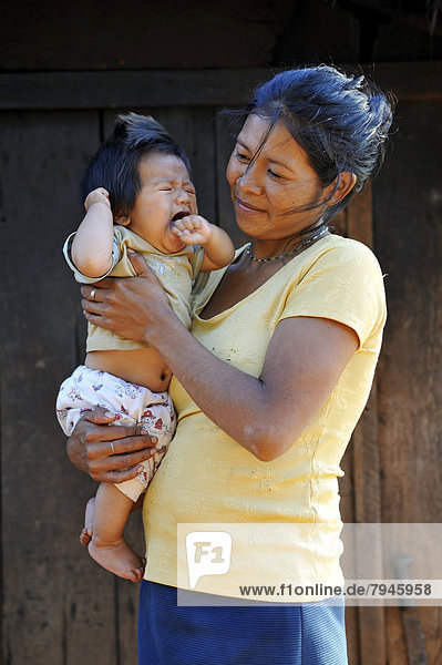 Young mother holding a crying child in her arms  in a community of Guarani Indians