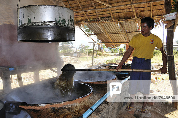 Man pouring sugar juice from one vessel to another  sugar cane processing