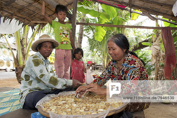 Woman pouring hot palm sugar in forms made of bamboo