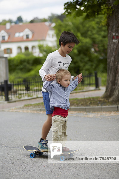 Großer und kleiner Bruder fahren mit dem Skateboard