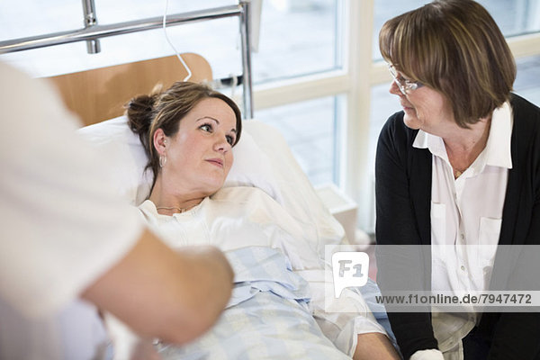 Seniorin sieht Tochter auf dem Bett liegend in der Krankenstation an