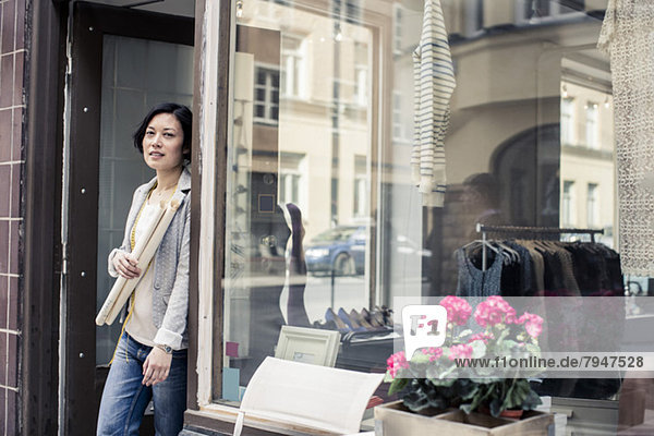 Porträt einer Modedesignerin mit Blaupause am Eingang des Ateliers