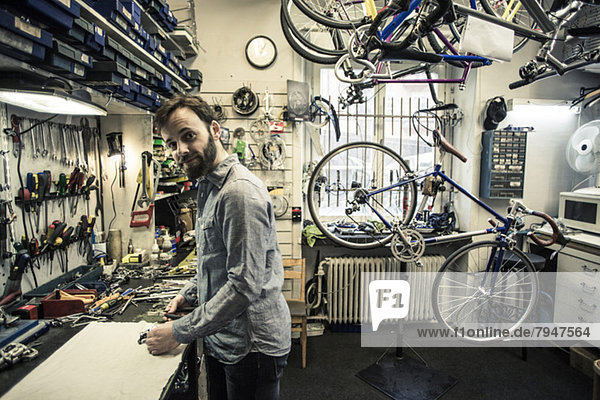 Side view portrait of mid adult repairman working at bicycle repair shop