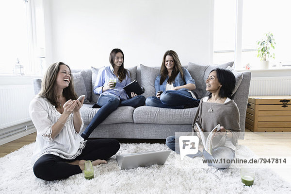 Weibliche Freunde die ihre Freizeit zusammen im Wohnzimmer verbringen.