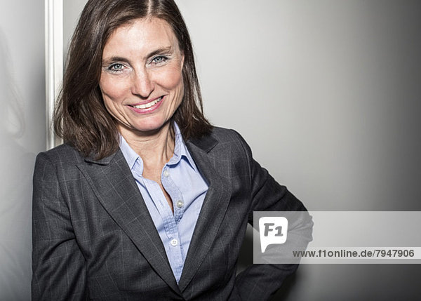 Portrait of mature businesswoman leaning on wall in office