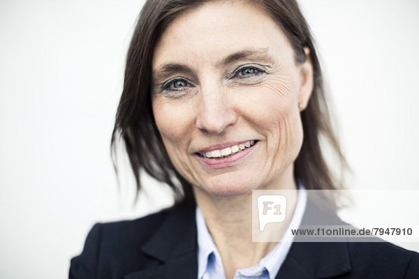Portrait of happy mature businesswoman against wall