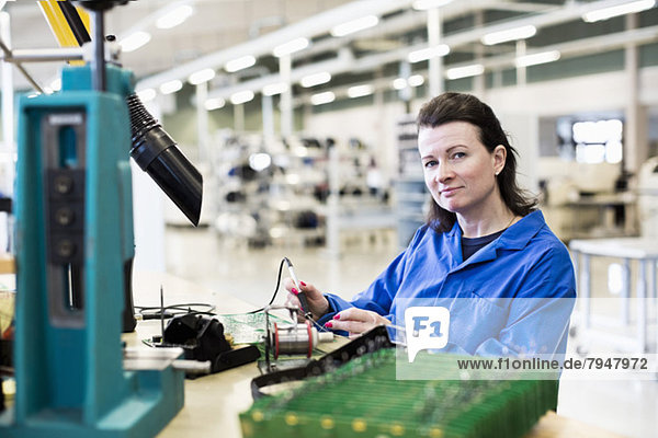 Porträt einer selbstbewussten Technikerin  die am Schreibtisch in der Industrie arbeitet.