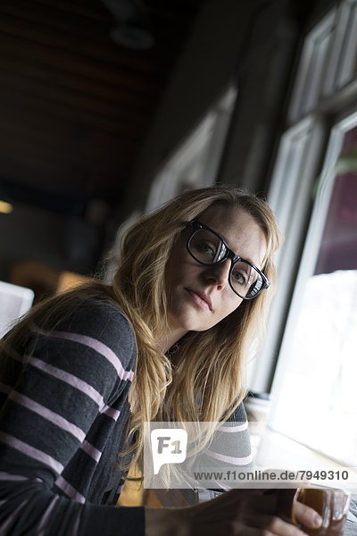 A young woman drinks coffee in a local cafe.