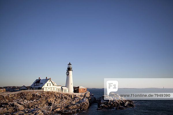 The early morning sun bathes Maine's Portland Head Light in a warm glow on a cold winter morning.