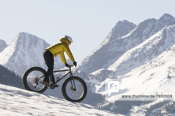 A woman riding a bike on the snow on Molas Pass  San Juan National Forest  Silverton  Colorado.