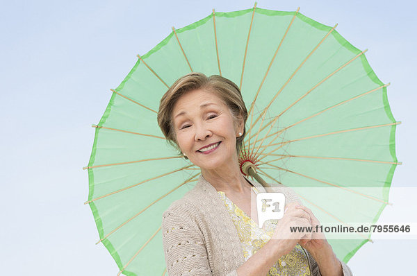 Portrait of senior woman holding green parasol