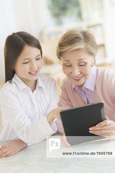 Granddaughter (8-9) and grandmother using digital tablet