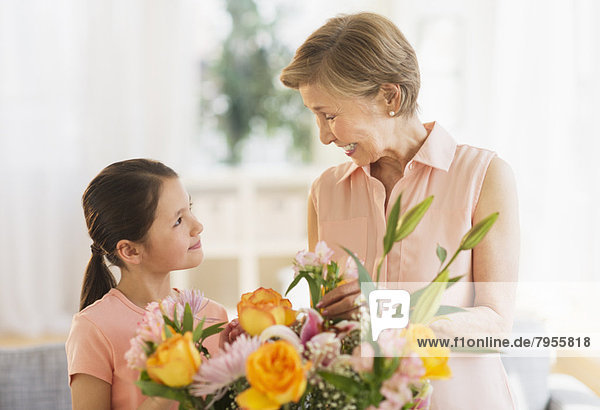 Granddaughter (8-9) and grandmother arranging flowers at home