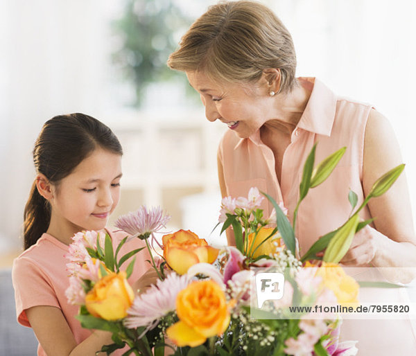 Granddaughter (8-9) and grandmother arranging flowers at home