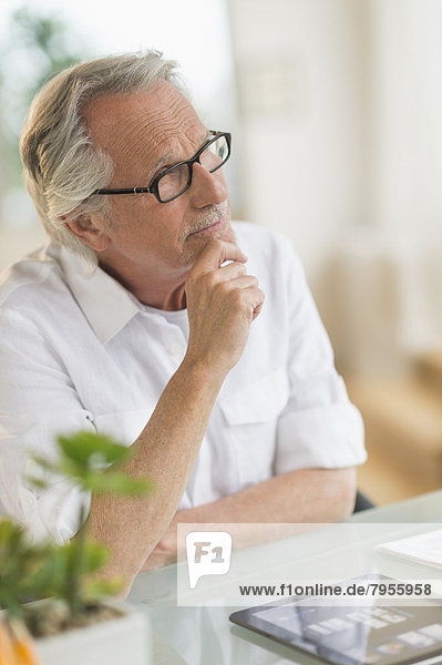 Portrait of senior man thinking at desk