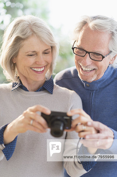 Smiling senior couple with digital camera