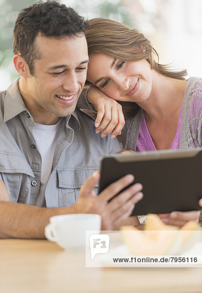 Young couple using digital tablet at kitchen table