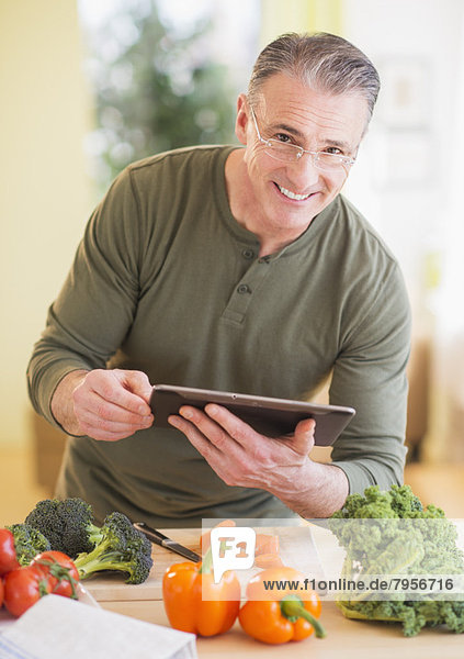 Portrait of man in kitchen  holding digital tablet