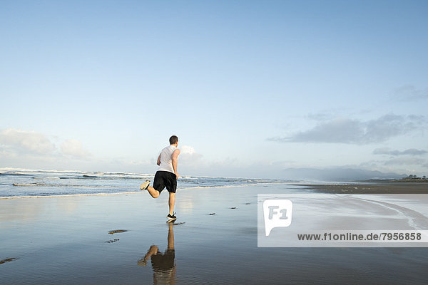 Young adult man running on beach