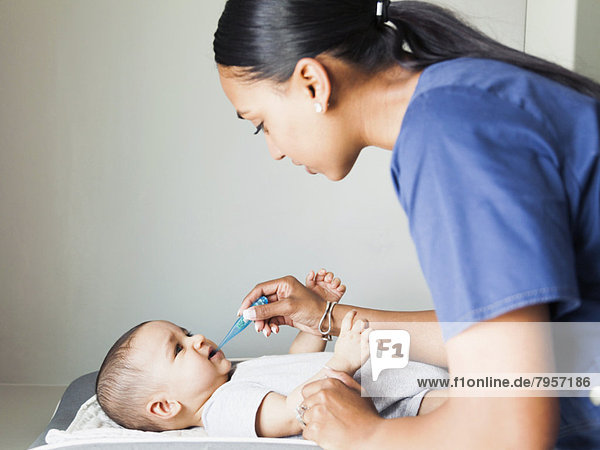 Nurse taking baby boy's (2-5 months) temperature