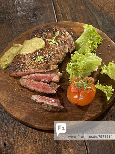 Gegrilltes Rib Eye Steak mit Kräutersauce auf Holzteller