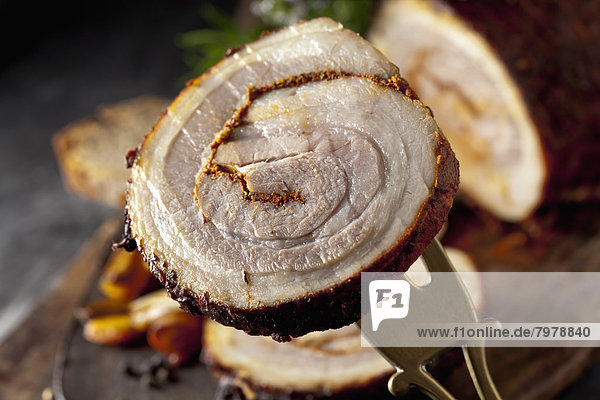 Rolled roast pork on wooden board  close up