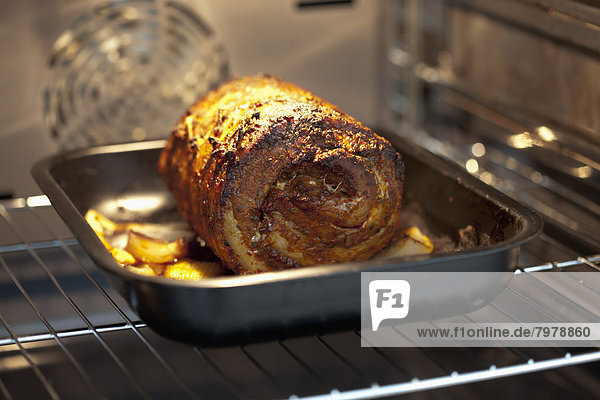 Gerolltes gebratenes Schweinefleisch auf Blech im Ofen  Nahaufnahme