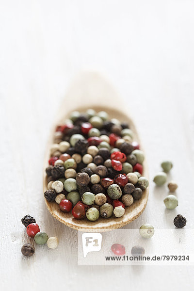 Variety of peppercorns on wooden spoon  close up