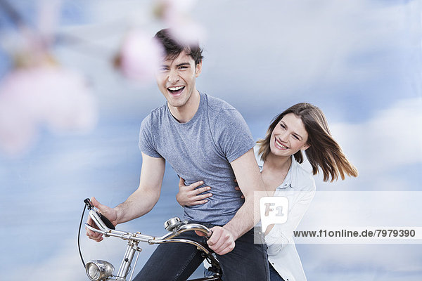 Germany  Cologne  Young couple having fun on bicycle  smiling