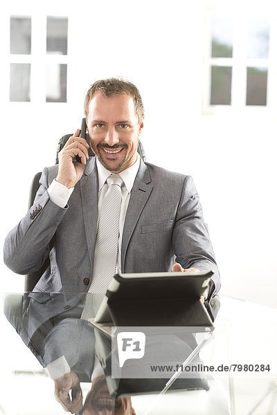 Germany  Portrait of businessman talking on mobile phone  smiling