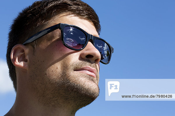 Porträt eines jungen Mannes mit Sonnenbrille und Blick in die Ferne