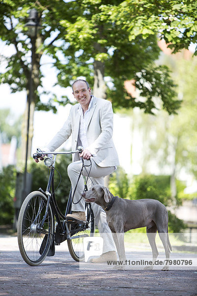 Portrait of mature man with Weimaraner dog and bicycle  smiling