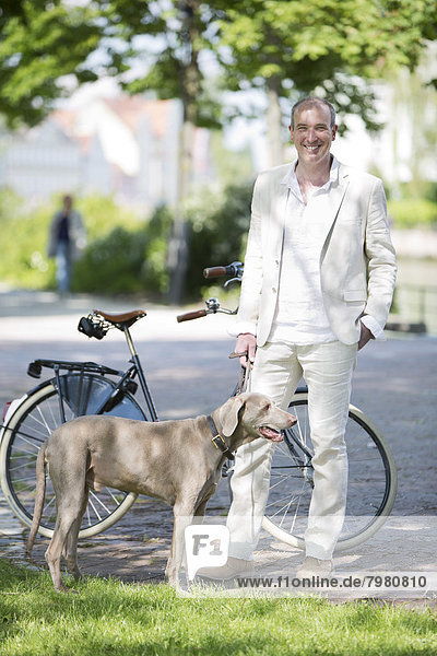 Porträt eines reifen Mannes mit Weimaraner Hund  lächelnd