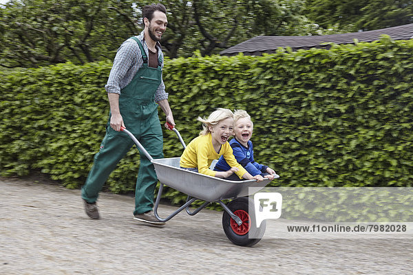 Germany  Cologne  Father carrying son in wheelbarrow  smiling